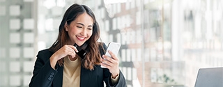 Businesswoman holding WaFd Bank Commercial credit card making a mobile purchase.