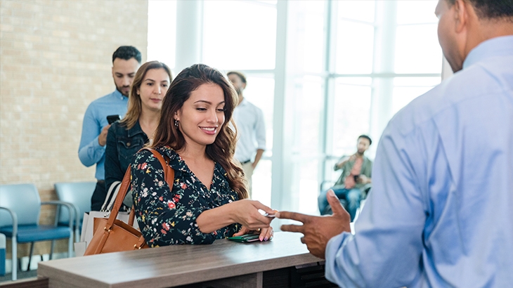 Woman handing bank teller a card.