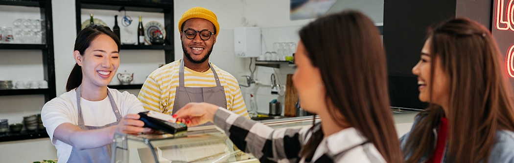 Women making a credit card tap payment at a shop counter.