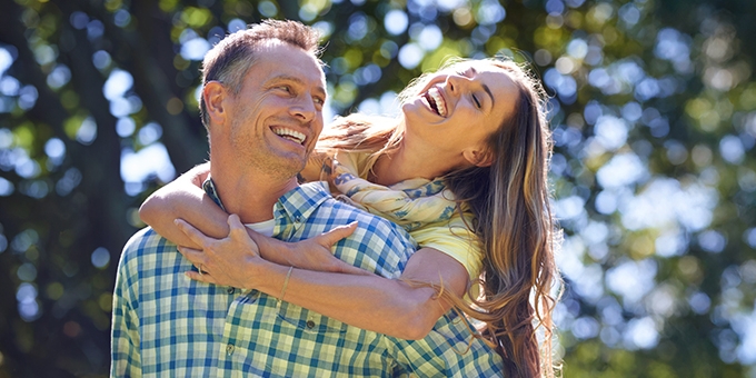 Couple laughing outside on a summer day.