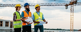 Engineer, architect, and contractor on the construction site with a crane in the background.