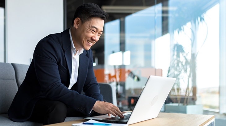 Businessman smiling and working on a laptop in the office.