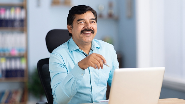 A businessman smiling while working on a laptop.