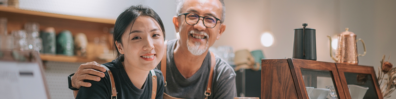 Father and daughter running their cafe, smiling at the counter. 