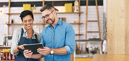 Coworkers using a digital tablet in a coffee shop.