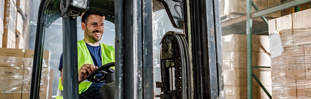 Warehouse worker driving a forklift in a storage room.