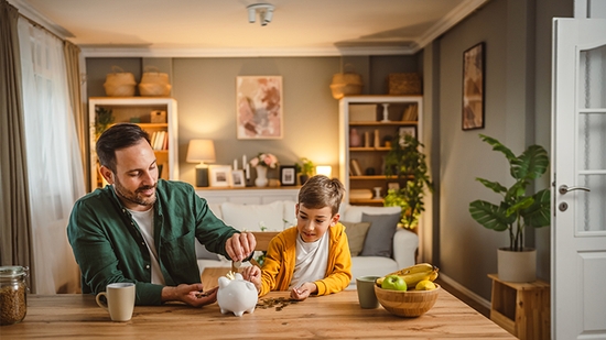 Father and son adding coins to a piggy bank.