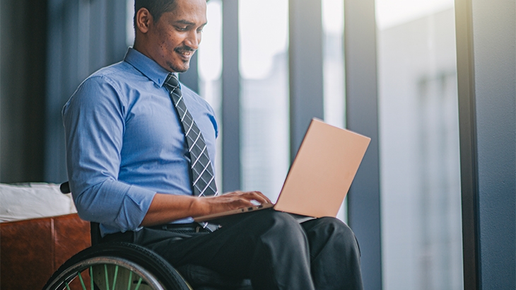 A businessman in a wheelchair working on a laptop.
