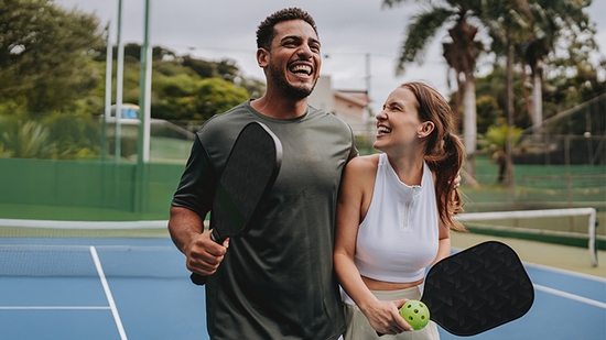 Compañeros de equipo riendo mientras juega pickleball.