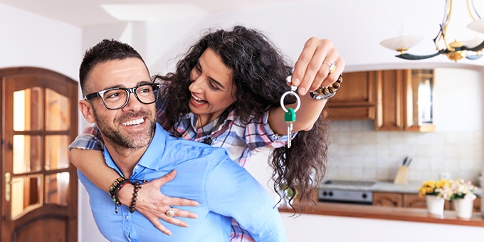 Young couple moving in new house, holding keys.