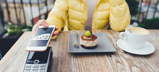 Woman paying for dessert with digital debit card mobile pay.