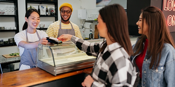 Women making a credit card tap payment at a shop counter.