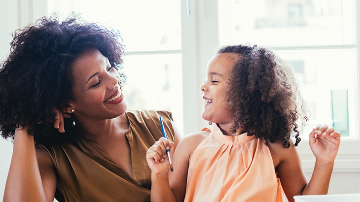 Madre e hija sonriéndose mientras pintan.