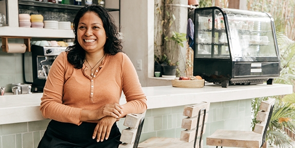 Business owner sitting at cafe bar stool.