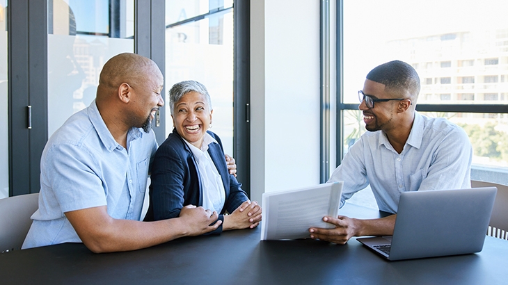 Couple smiling while going over savings account options with financial advisor.
