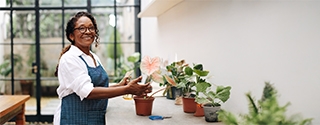 A woman smiling while potting a plant in her shop.
