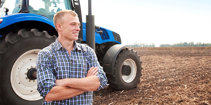 Farmer standing in front of a tractor.