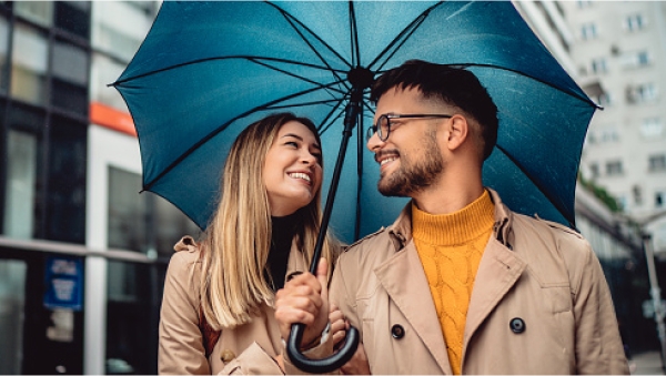Young couple standing in the rain under an umbrella