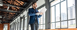 A Businessman walking through an empty office building, looking at his laptop.