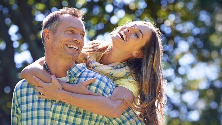 Couple laughing outside on a summer day.
