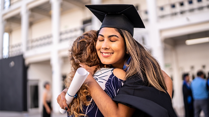 Young graduate woman embracing her mother on graduation.