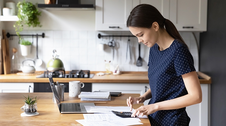 Woman using calculator to manage expenses.  