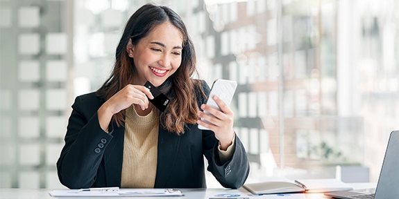 Businesswoman holding WaFd Bank Commercial credit card making a mobile purchase.