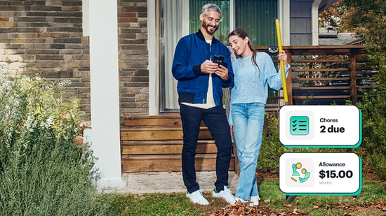 Teenager raking leaves, father paying her for the chore on his mobile phone.
