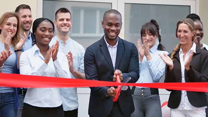 A new business owner cuts a ribbon to celebrate the grand opening