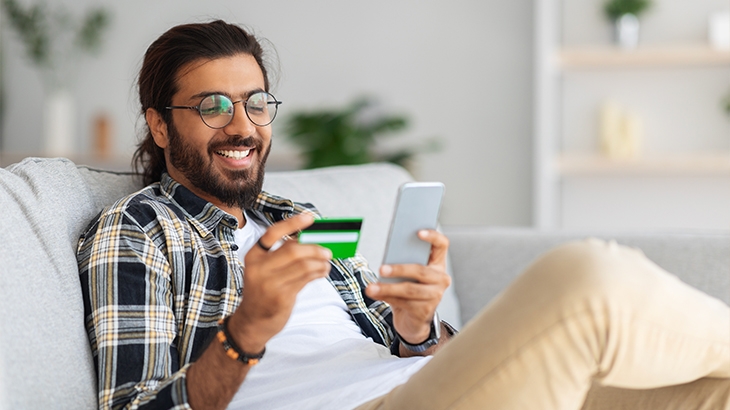 Man holding a credit card making a mobile phone payment.