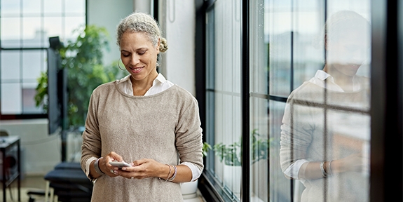 Businesswoman in office checking her mobile phone.
