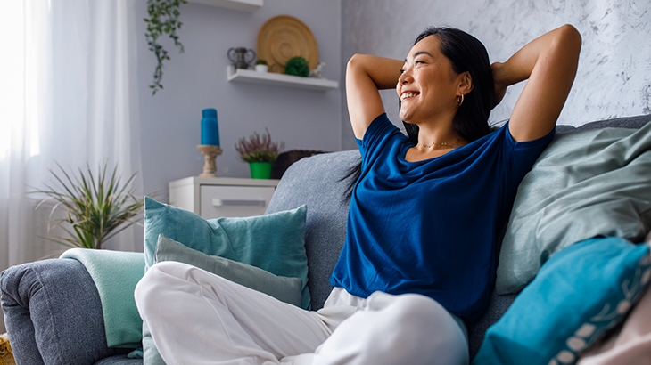 Woman on sofa relaxed, smiling, and daydreaming