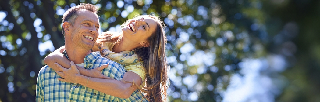 Couple laughing outside on a summer day.