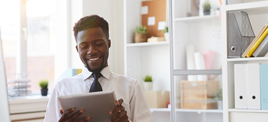 Young businessman with tablet sitting at desk in office.