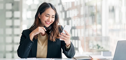 Businesswoman holding WaFd Bank Commercial credit card making a mobile purchase.