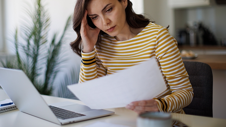 Woman looking stressed while looking at a document.