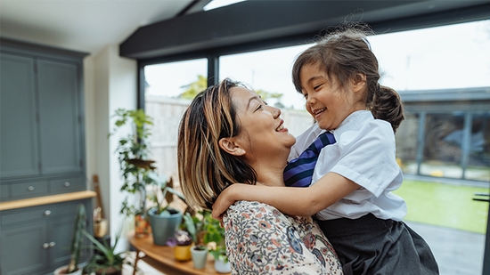 Madre sosteniendo a su hija pequeña y sonriendo.