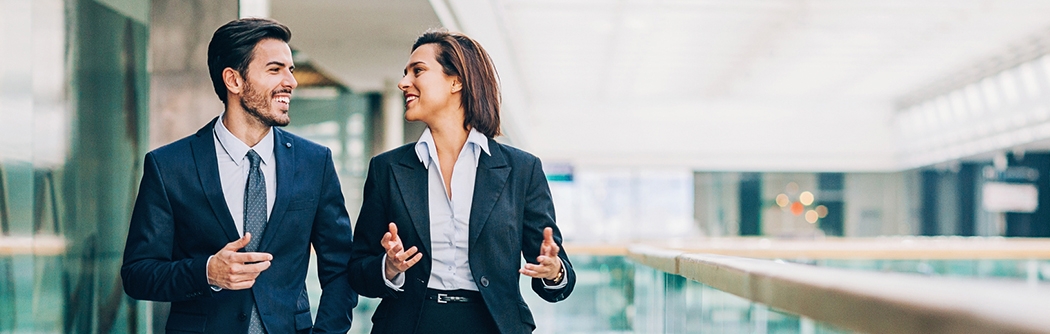 Two business people walking and talking in an office building