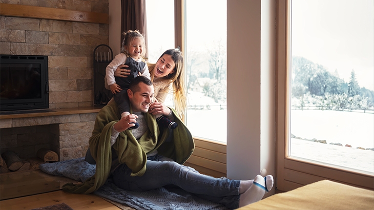A young family laughing while in the living room on a winter day.