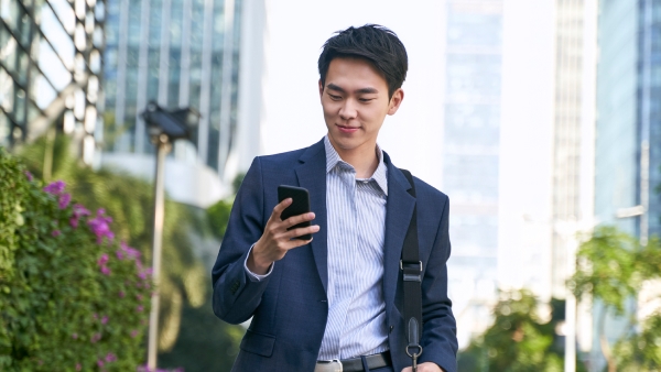 Young Asian businessman using a smartphone while walking