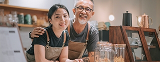 Father and daughter running their cafe, smiling at the counter. 