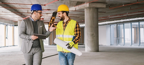 Construction worker and architect talking in building under construction.