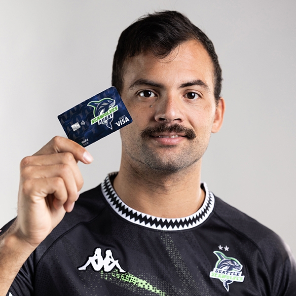 Seattle Seawolves player holding WaFd Bank Seawolves debit card by face.