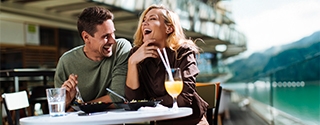 Una pareja riendo mientras come en un café al aire libre.