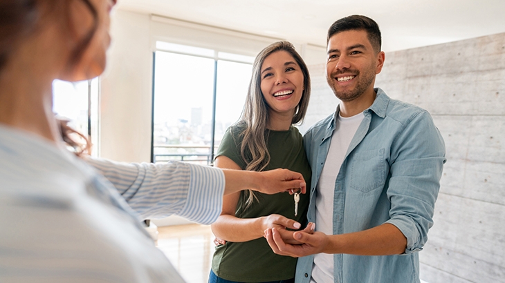 Real estate agent giving the keys of their new house to a happy couple