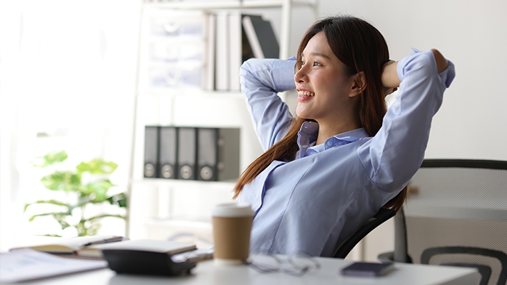 A businesswoman relaxing with her hands behind her head.