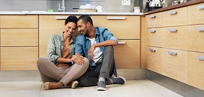 Smiling young couple sitting together on their kitchen floor.