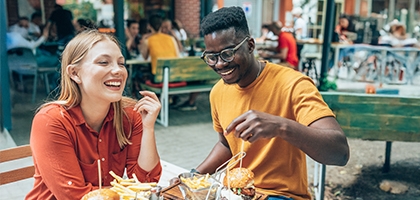 Friends having fun eating burgers and fries at an outdoor restaurant.