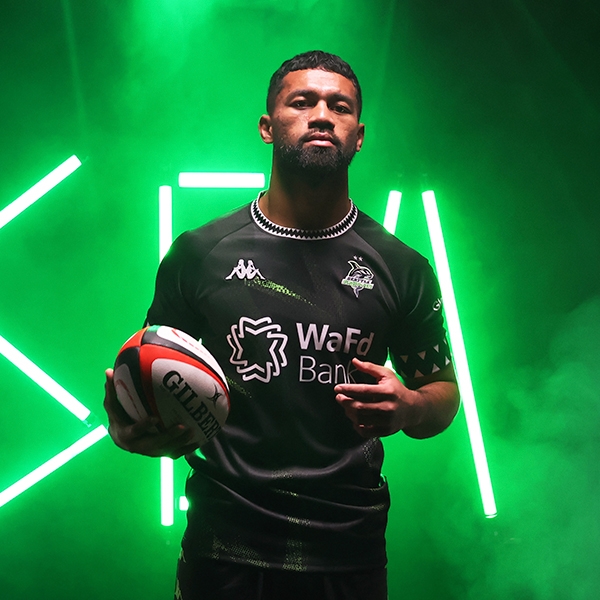 Seattle Seawolves player holding football in front of neon green lights.
