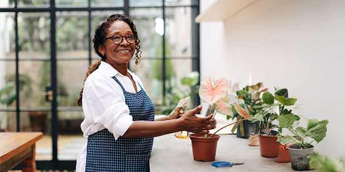 A woman smiling while potting a plant in her shop.